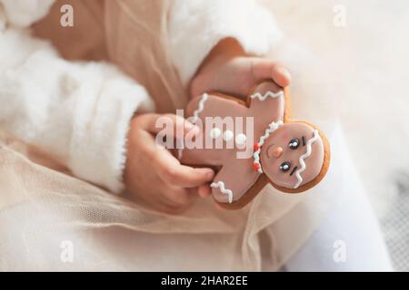 Mani di bambina che tiene un regalo di natale dolce e carino per i bambini - biscotto uomo pan di zenzero Foto Stock