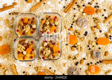 Tradizionale dessert turco Ashure o Noah's Pudding in ciotole quadrate di vetro su ingredienti di Ashure Dessert Foto Stock