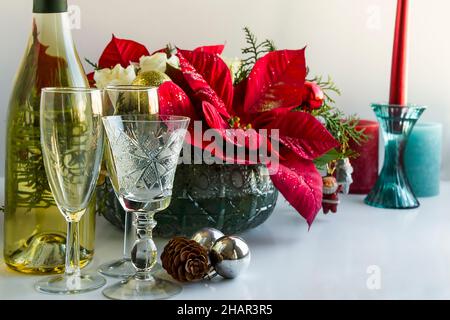 Tavolo da pranzo di natale o di Capodanno con ornamenti speciali, fiore poinsettia, bottiglia di champagne. Foto Stock