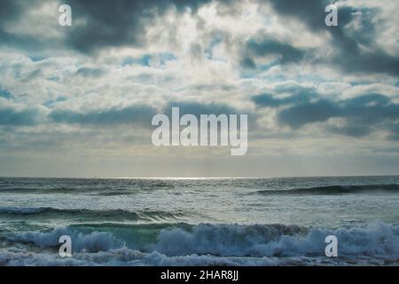 Seacape con raggi solari e nuvole scure. I raggi del sole brillano attraverso le nuvole scure e si riflettono nell'acqua del mare. Foto Stock