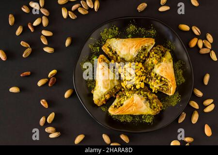 Tradizionale Dessert Turco Pasticceria è Pistacchio Baklava; Sobiyet, piatto nero su sfondo nero con pistacchio Nut Foto Stock