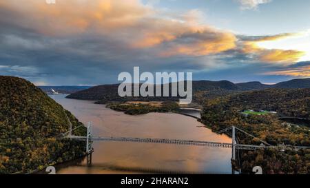 Bellissimo scatto di un magnifico tramonto colorato sul fiume circondato da montagne boscose Foto Stock