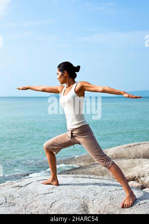 Donna che pratica lo Yoga sulla spiaggia a Kamalaya, Koh Samui, Thailandia. Una donna pratica yoga mattutino sulla spiaggia di Ao Thai al resort Kamalaya. Foto Stock