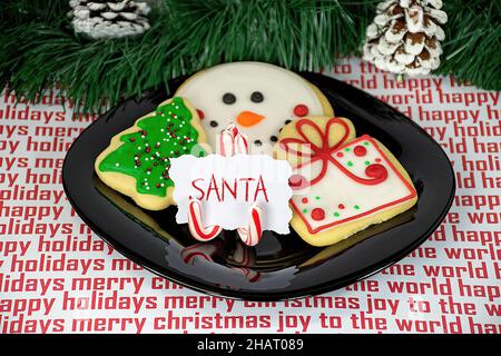 Biscotti di zucchero di Natale con la canna da zucchero porta carte per Babbo Natale su piatto nero Foto Stock