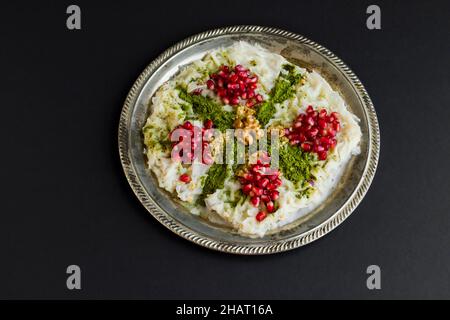 Tradizionale Ramadan Dessert Gullac su piatto di metallo d'epoca decorato con semi di melograno, nocciole tritate e pistacchi Foto Stock