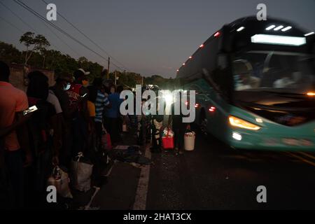 Tapachula (Messico), 14 dicembre 2021, migliaia di haitiani si allineano e attendono autobus, come quello a destra dell'immagine, forniti dall'Istituto Nazionale Migrazioni Messicano per portarli in altre città del Messico. INM è autobus i migranti per alleviare le sopraffatte autorità migratorie e di asilo nella città di Tapachula, al confine con il Guatemala. Ogni autobus si dirigeva verso una destinazione diversa. I migranti, molti dei quali erano in attesa in linea da più di una settimana, non avevano scelta di destinazione. Molte persone erano ammalate di tosse e di febbre alta. Credit: Lexie Harrison-Cripps Foto Stock