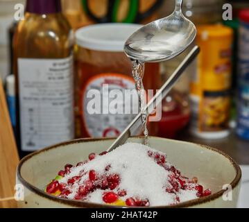 Lo chef aggiunge sciroppo all'insalata di frutta a casa in cucina. Foto Stock