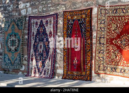 Tappeti fatti a mano appesi su un muro in una strada mercato orientale o bazar a Istanbul, Turchia Foto Stock