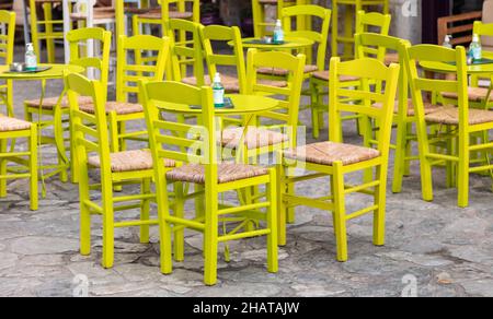 Bar all'aperto. Posti a sedere vuoti su sfondo di vicolo di ciottoli. Areopoli, mani Grecia. Tipica caffetteria all'aperto di strada rotonda tavoli di metallo e legno Foto Stock