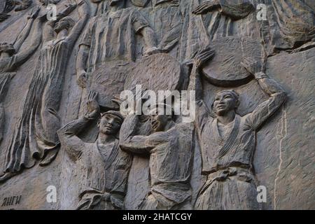 Il fregio in bronzo opere d'arte Socialista alla metropolitana Mustakillik Maydoni, ingresso della metropolitana. Uomini che tengono le ruote. A Tashkent, Uzbekistan. Foto Stock