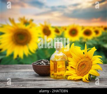 Olio di girasole in bottiglia e semi con fiori di girasole Foto Stock