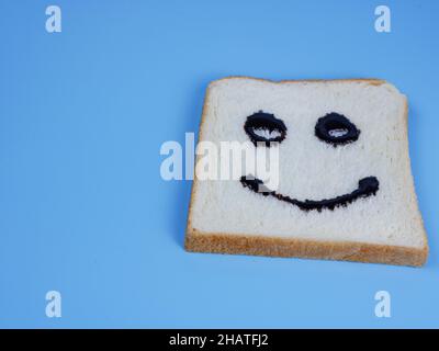 pane bianco con emoticon sorridente su sfondo pastello blu Foto Stock