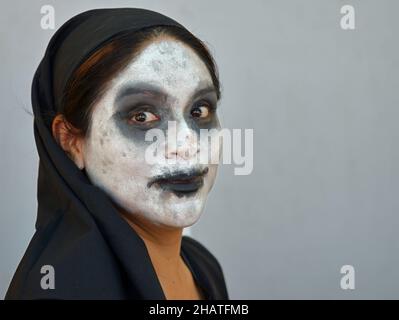 La giovane donna messicana con il tradizionale viso bianco zombie-simile Catrina il giorno dei morti (Día de los Muertos) indossa abiti neri. Foto Stock