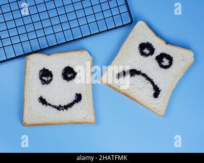pane tostato con emoticon smiley e tristi, per il concetto di felicità e tristezza Foto Stock