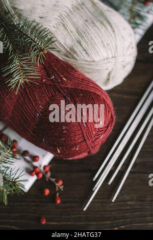 Matasse di filo di lana con aghi su sfondo scuro. Concetto per vita lenta fatta a mano e hygge. Foto Stock