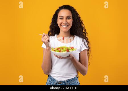 Ritratto di sorridente Latino Lady Holding Plate con insalata Foto Stock