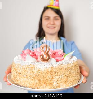 Il medico o l'infermiere tiene una torta di compleanno con il numero tre per l'anniversario dell'apertura della clinica Foto Stock