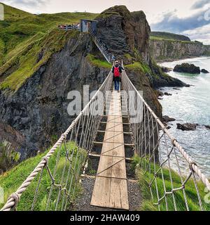 Stretto ponte sospeso per pedoni sulla costa rocciosa, isola disabitata di Carrick-a-Rede, Contea di Antrim, Irlanda del Nord, Gran Bretagna Foto Stock