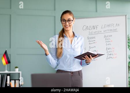 Studiare tedesco online. Ragazza allegra insegnante che dà online lezione di lingua straniera, utilizzando il laptop Foto Stock