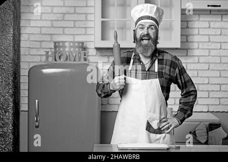 Bel cuoco di guef con becco che prepara gli spaghetti su una cucina. Chef cucina pasto. Foto Stock