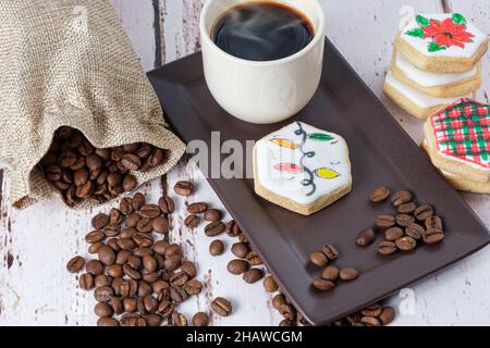 Biscotti al burro a tema natalizio accanto ai chicchi di caffè e alla tazza. Foto Stock