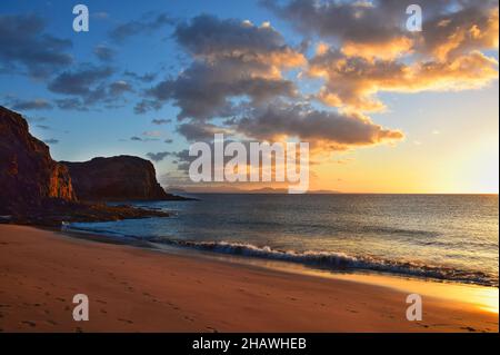 La costa occidentale di Lanzarote al tramonto. Una spiaggia sabbiosa e un cielo blu con alcune nuvole. Isole Canarie, Spagna. Foto Stock