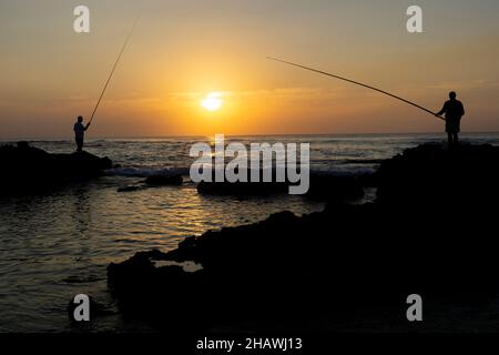 Due pescatori che si godono l'ultima luce del sole sulla spiaggia in Israele Foto Stock