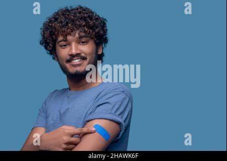 Uomo contento che dimostra il gesso sul suo braccio dopo la vaccinazione Foto Stock