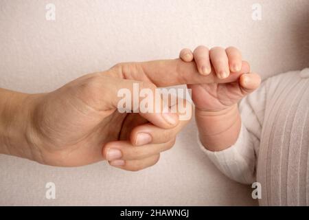 Il neonato bianco si chiude con una presa salda sul dito del genitore Foto Stock