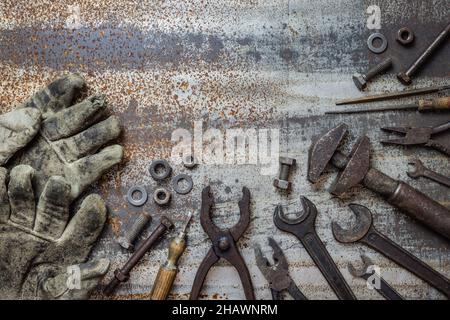 Variazione di vecchi attrezzi di idraulico su fondo di metallo arrugginito, disposizione piatta con spazio di copia. Pinza, chiave, guanto, vite e altre attrezzature industriali sulla linguetta Foto Stock