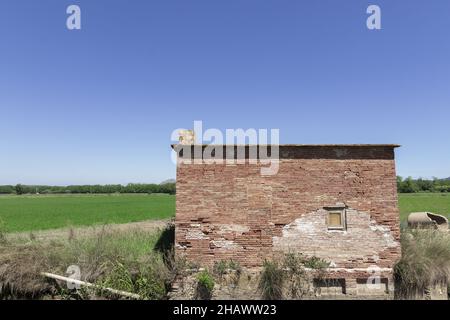 Piccolo vecchio edificio in mattoni sul campo erboso in campagna Foto Stock