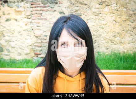 Primo piano ritratto di bella ragazza caucasica in una felpa con maschera e parete di roccia sullo sfondo. Foto Stock