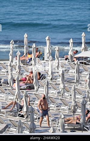 I vacanzieri che indossano maschere protettive per proteggere contro Covid-19 sono visti dai lettini di un hotel a Tenerife, Spagna. Dicembre 2021. Foto Stock