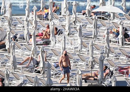 I vacanzieri che indossano maschere protettive per proteggere contro Covid-19 sono visti dai lettini di un hotel a Tenerife, Spagna. Dicembre 2021. Foto Stock