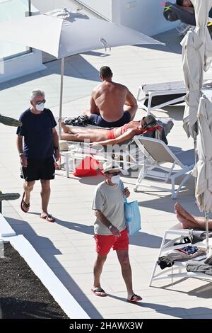 I vacanzieri che indossano maschere protettive per proteggere contro Covid-19 sono visti dai lettini di un hotel a Tenerife, Spagna. Dicembre 2021. Foto Stock