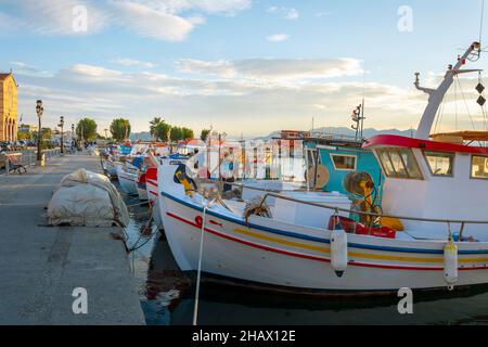 Colorate barche da pesca costeggiano il porto dell'isola greca di Egina, Grecia al tramonto, con il lungomare in vista. Foto Stock