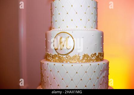 torta nuziale a sei piani con lettera m incisa e pizzo giallo e nastro rosso Foto Stock