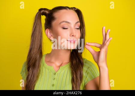 Ritratto di bella ragazza sognante divertente degustazione invisibile piatto isolato su sfondo di colore giallo vibrante Foto Stock