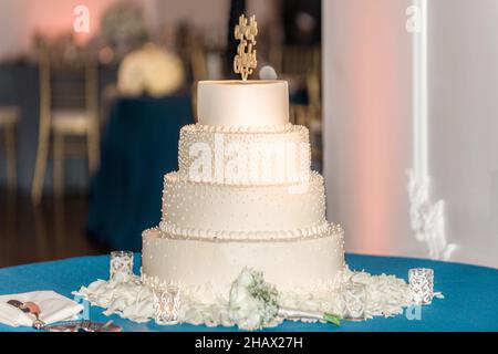 torta nuziale bianca a tre piani con perle bianche e fiori in elevazione Foto Stock