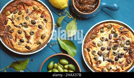 Torta fatta in casa con olive su vecchio sfondo di legno blu decorato con limone fresco, olive fresche, foglie di limone e marmellata di fichi dall'alto Foto Stock