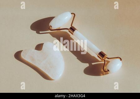 Kit massaggio viso con rullo per il viso in giada e massaggiatore gua sha in pietra naturale Foto Stock