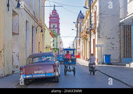 Cattedrale, auto d'epoca americana classica e bicitaxi / taxi in bicicletta nel centro storico della città Camagüey sull'isola Cuba, Caraibi Foto Stock