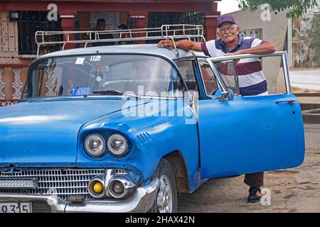 Tassista cubano in posa con taxi auto blu americano classico nella città Florida, provincia di Camagüey sull'isola Cuba, Caraibi Foto Stock