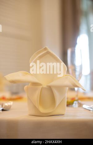 tovagliolo di stoffa bianco piegato in modo elegante al tavolo da pranzo Foto Stock