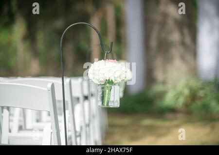 Bouquet Hydrangea bianco in vasi di vetro decorazioni appese all'isola per cerimonie di nozze all'aperto con sedie bianche Foto Stock
