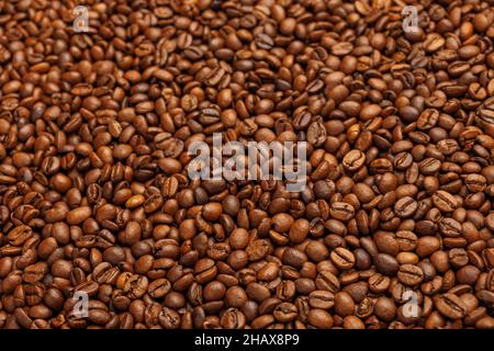 primo piano sfondo a cornice completa di chicchi di caffè torrefatti su una superficie piana di legno con messa a fuoco selettiva Foto Stock