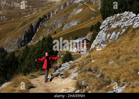 Trekking, Wandern Dolomiten, schöne Frau wandert auf Berge und Felsen am Langkofel, Sasso lungo mit Blick und Aussicht auf eine Berghütte a Südtirol Foto Stock