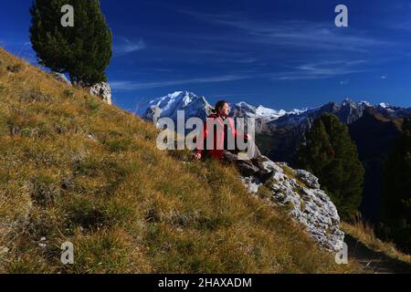 Dolomiten, schöne Frau wandert auf Berge und Felsen am Langkofel, Sasso lungo mit Blick und Aussicht auf die Marmolada, Marmolata in Südtirol Foto Stock