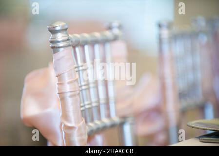 Sedie chiavari dorate con archi rosa e nastri alla cerimonia di nozze del country club Foto Stock