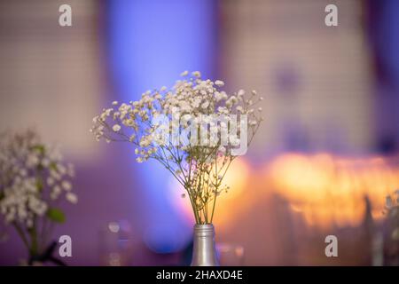Bambini alito fiori centropice in bottiglia d'argento con illuminazione calda sullo sfondo Foto Stock